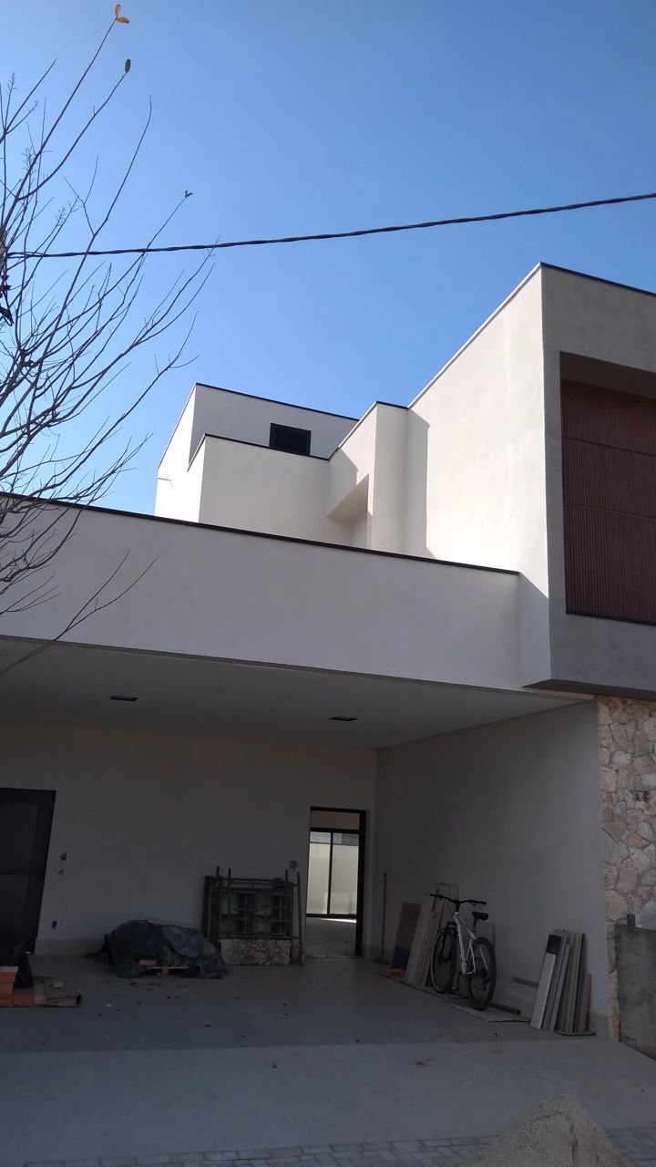 Fachada residencial moderna pintada de branco, com céu azul ao fundo